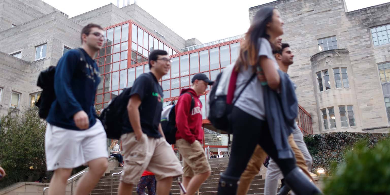 A group of students walks behind Jordan Hall.